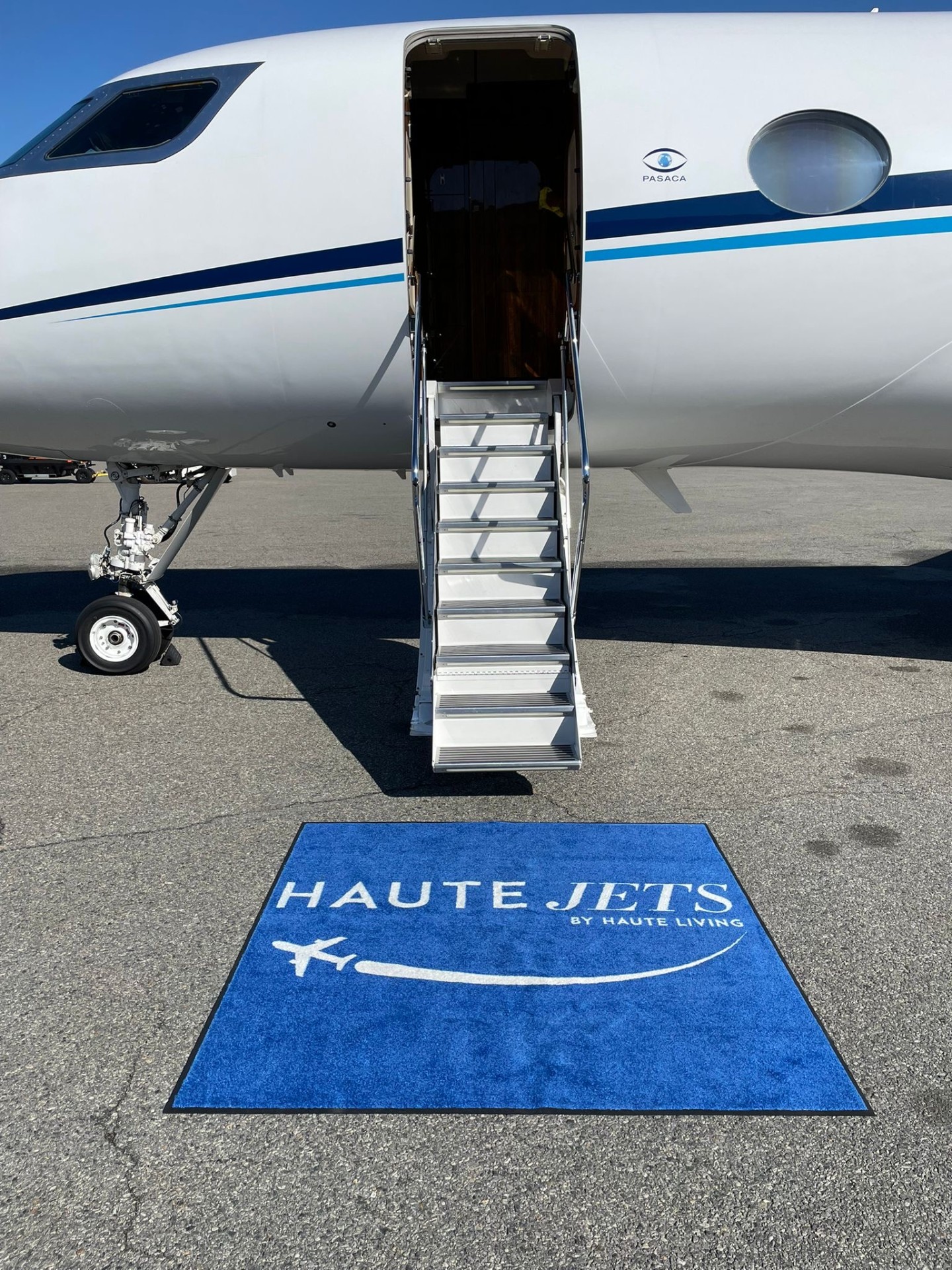 Haute Jets branded welcome carpet at the base of a private jet stairway on the tarmac